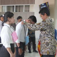 Direktur Akmet, Bapak Vera Firmansyah, M.Si., menyerahkan tanda pengenal kepada mahasiswa baru sebagai simbol dibukanya kegiatan PKKMB 2025 dalam Sidang Senat Terbuka